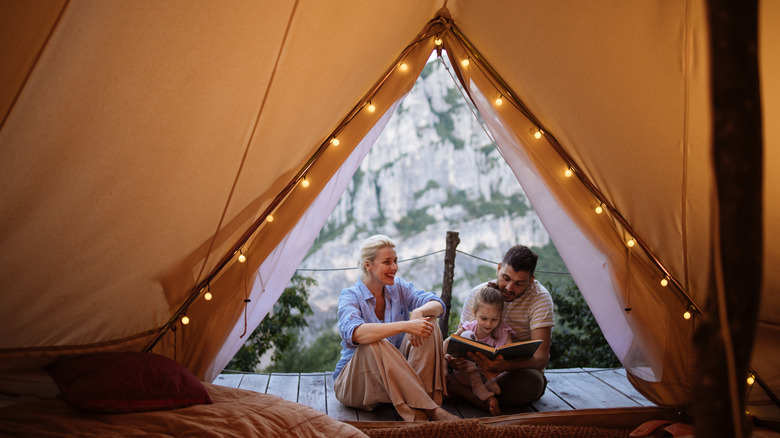 Parents reading a child a book in a large tent with LED lights.