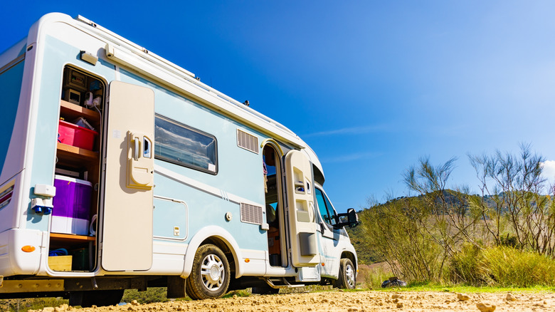 A camper RV with an open storage compartment.