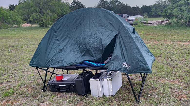 tent cot elevated above ground with items stored beneath