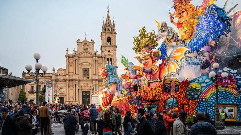 Vivid giant puppets and parade floats in front of a Baroque church in Acireale