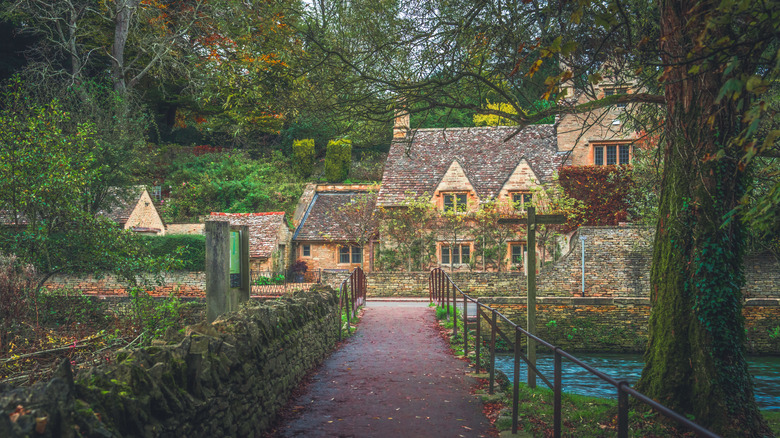 a footbrige over a calm stream and a row of cottages