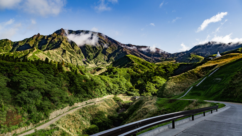 a road leading up to a grass covered mountain