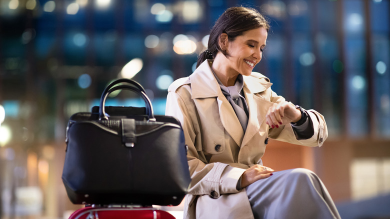 Woman with luggage checking watch