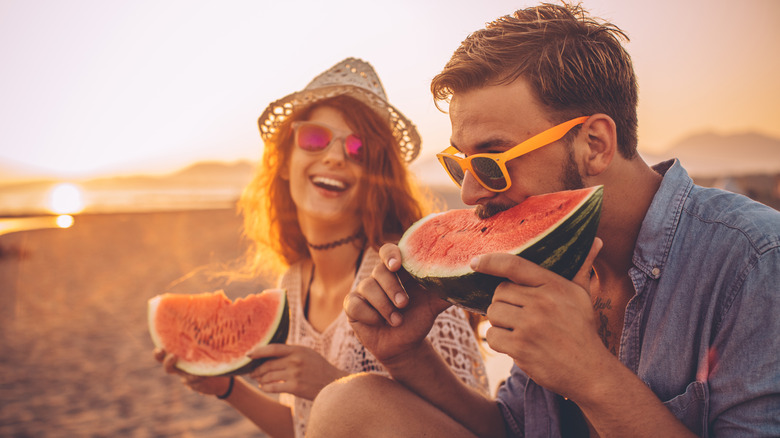 couple eating watermelon on beach