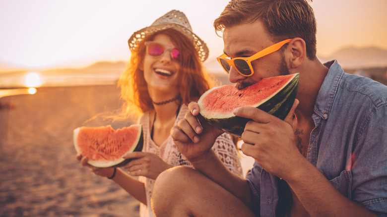 Couple eats watermelon on the beach