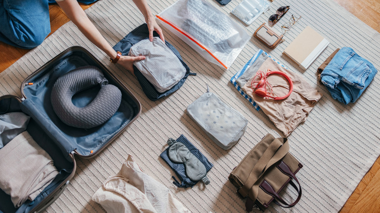 person packing items in suitcase