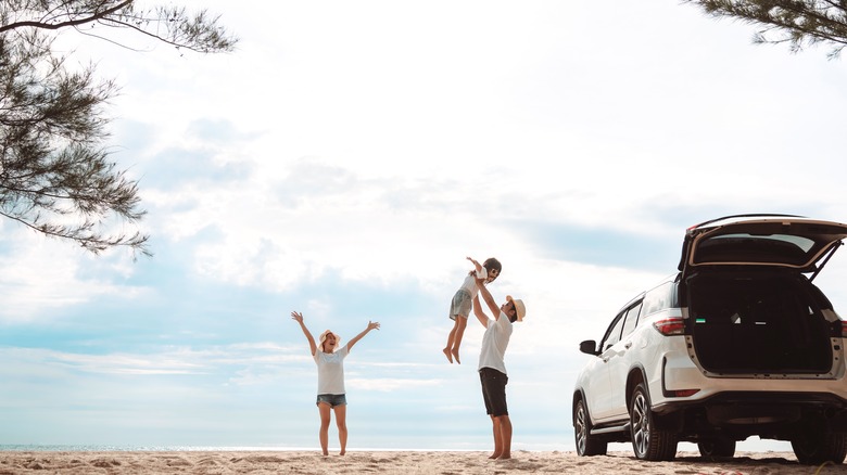 family on beach with car