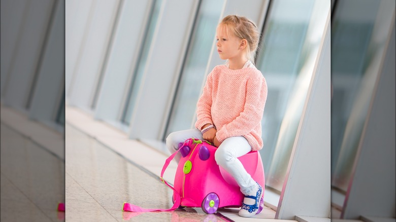 Girl on ride-on suitcase 