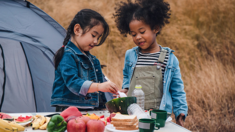 Two kids helping to cook while camping.