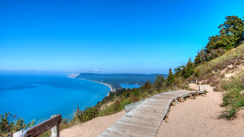 A boardwalk through Sleeping Bear Dunes next to brilliant turquoise waters.