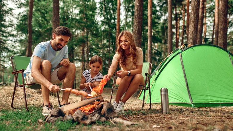 Family cooking over a fire at a campsite