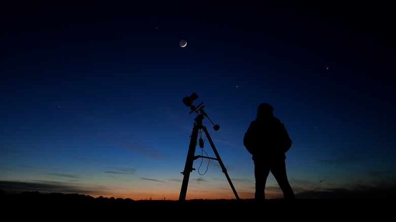 a person standing with a telescope for stargazing