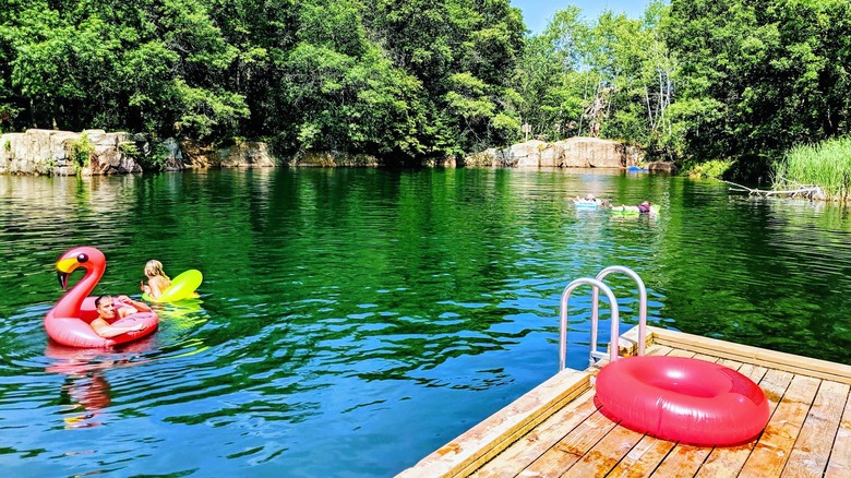 swimmers in colorful floaties near a dock in one of the swimming quarries at Quarry Park & Nature Preserve