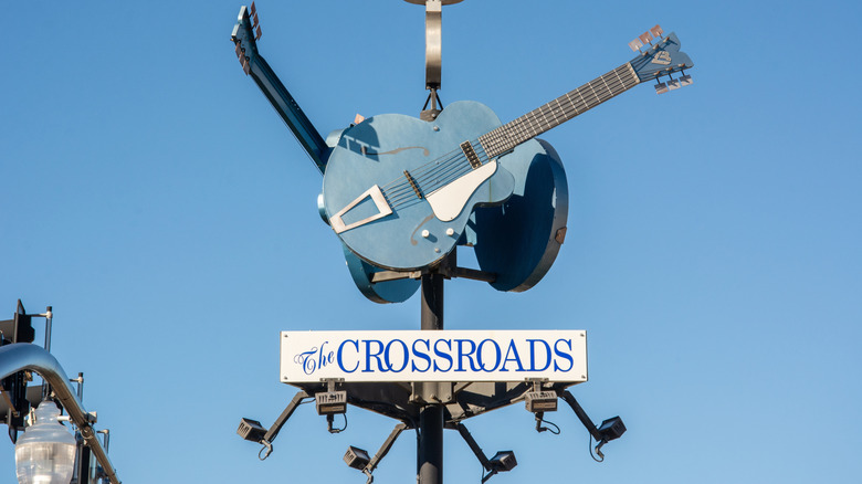 top of a streetlamp with guitars and The Crossroads sign