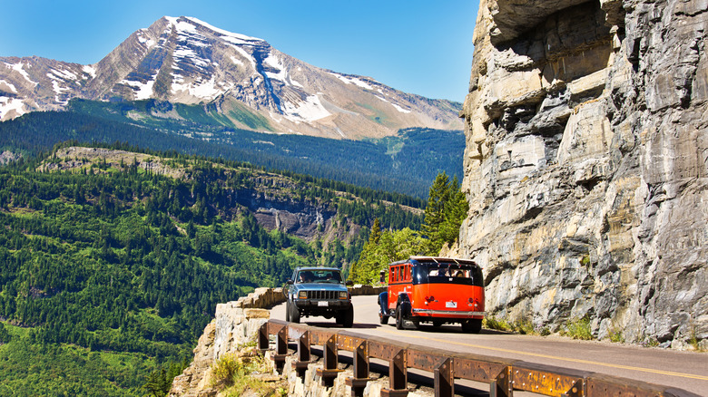 a vintage red bus passes another car on a mountain road