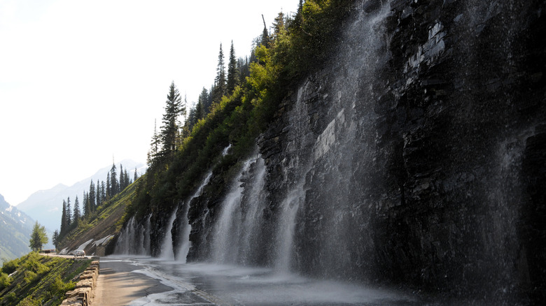 waterfalls falling onto a mountain road