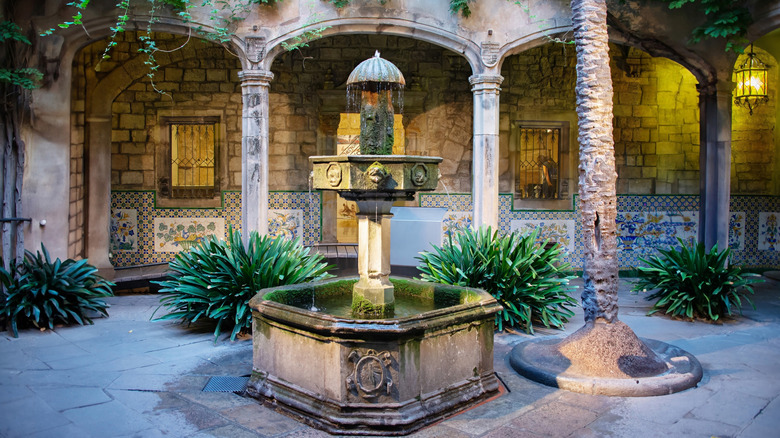 Octagonal fountain surrounded by arched columns, foliage and decorative tiles in the Picasso Museum in Barcelona
