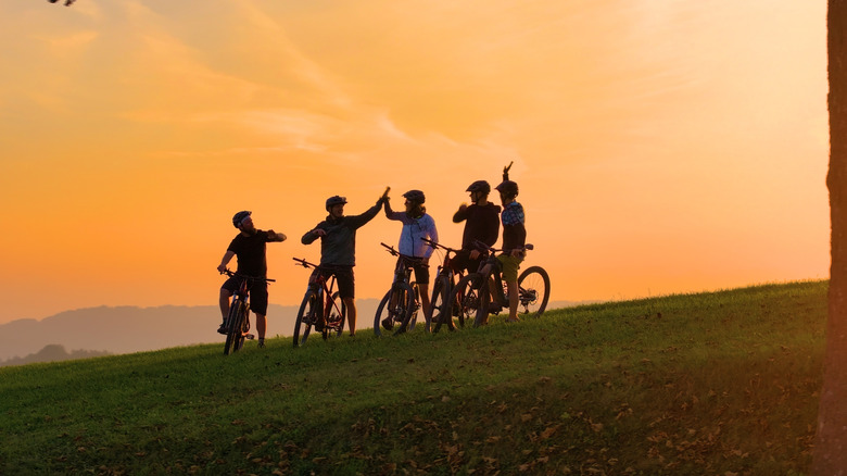 A group of five men on mountain bikes on the side of a hill at dusk