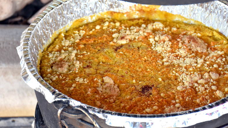 Peach cobbler cooking in a Dutch oven