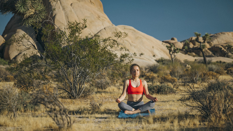 A young woman meditates in the desert
