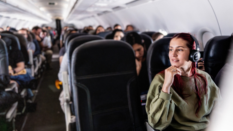 Young woman listening to music while traveling by plane
