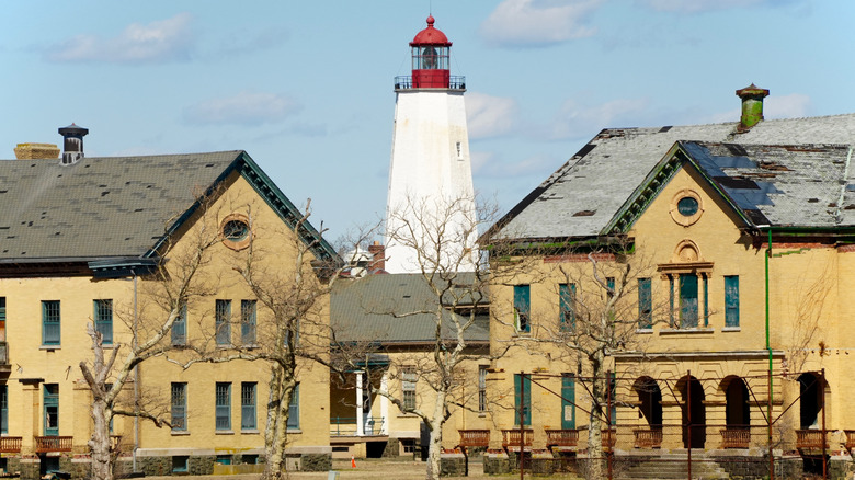 The yellow historic buildings and white and red lighthouse of Fort Hancock, in Sandy Hook, New Jersey