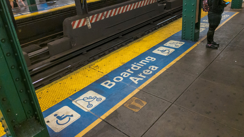 Accessibility signs painted on the ground of a New York subway station.