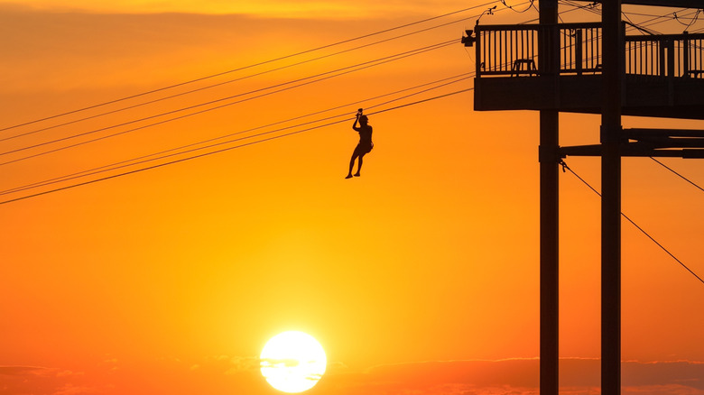 Silhouette of a person on the zipline at WildPlay Element Parks Jones Beach during sunset