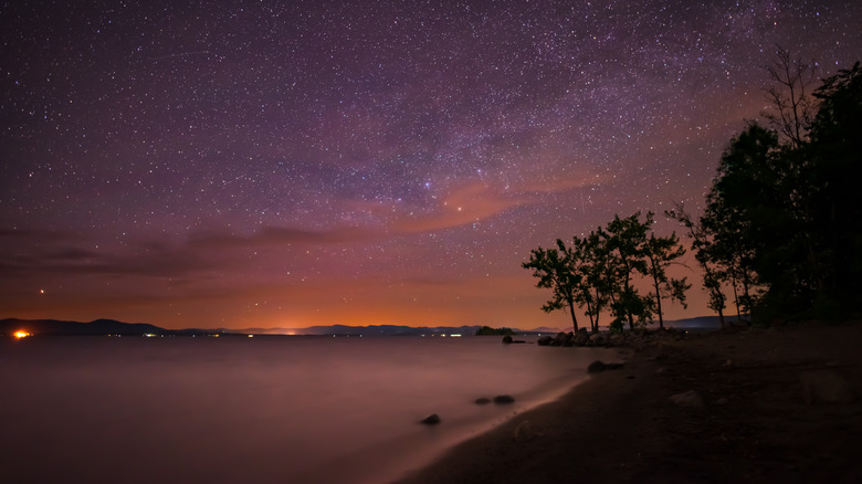 A view across Great Sacandaga Lake at night, with a pink starry sky