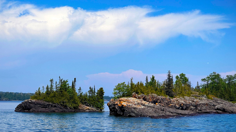 Blue sky and clouds over the dark blue waters of Lake Superior around forested islands near Isle Royale National Park in Michigan