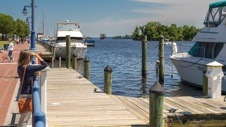 Riverside boardwalk with boats and pedestrians