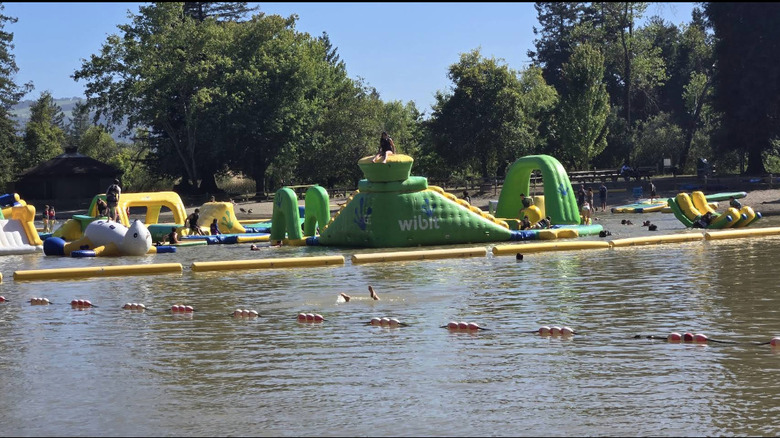 Children swim and play on the inflatable water park at Spring Lake Regional Park.