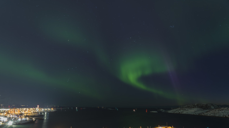 the aurora borealis lights up the sky above the bay