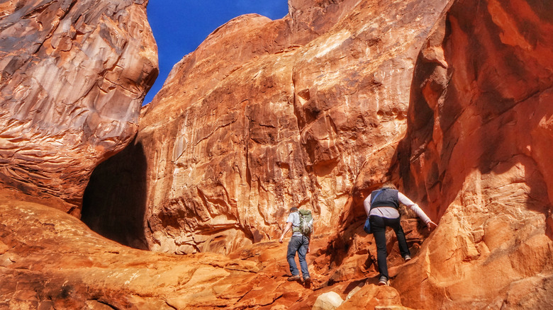 hikers near sheer cliffs in the Fiery Furnace section of Arches National Park in Utah