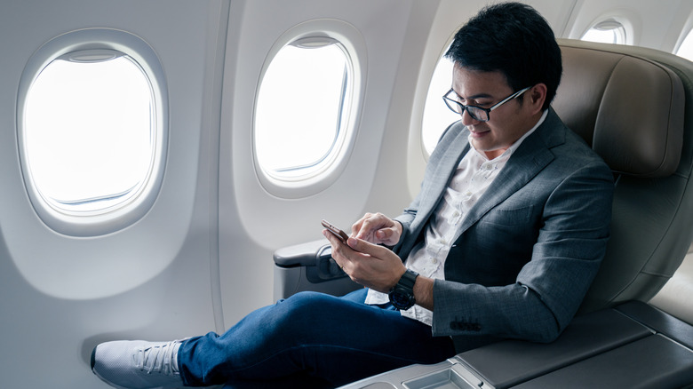 Man using cellphone on plane