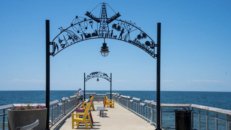 Historic ironworks sign of Euclid Beach Park arches over a pier stretching into Lake Erie, Ohio