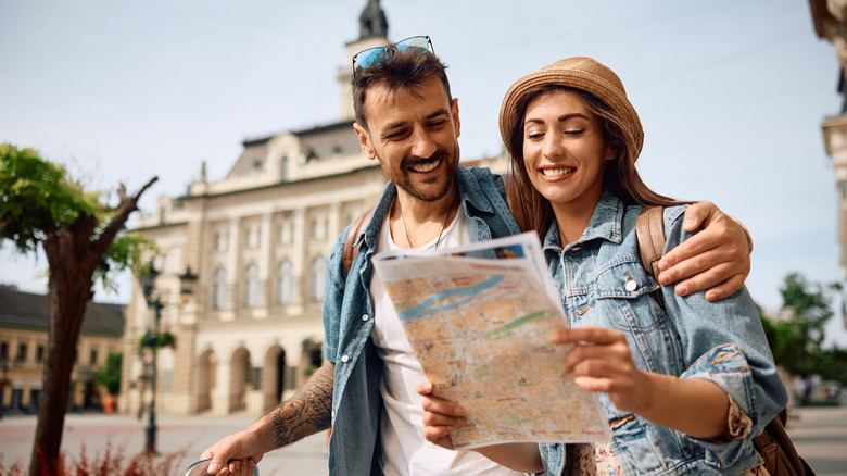 happy couple enjoying in travel while exploring a map during their walk through the town.