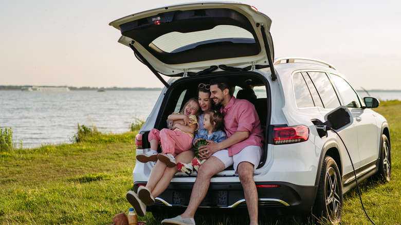 Happy family sitting in the car trunk while on road trip