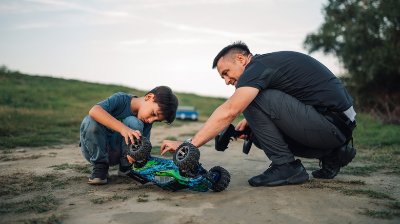 Cheerful dad watching his son playing with car toy