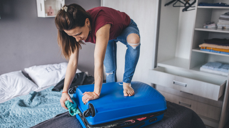 woman standing on suitcase