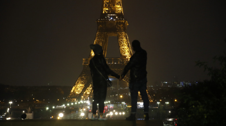 Couple looking at the Eiffel Tower lit up at night in Paris