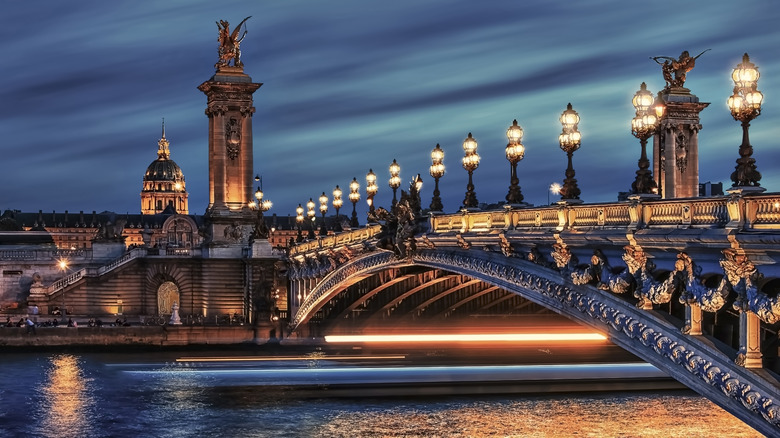 bridge with streetlights, water reflection, statues