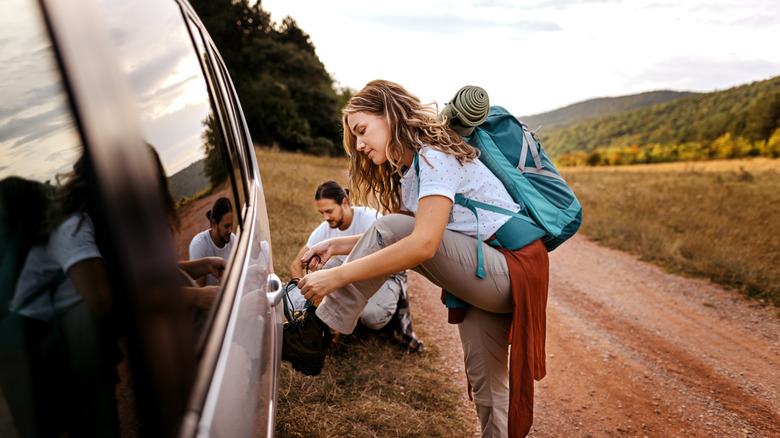 woman tying shoelaces with car support beside a man