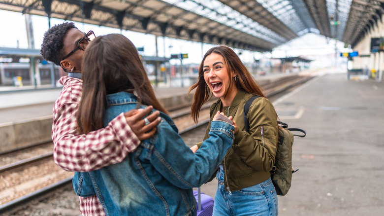 Three friends greeting each other in a train station.