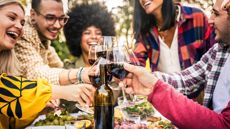 A group of diners toasts their wine glasse