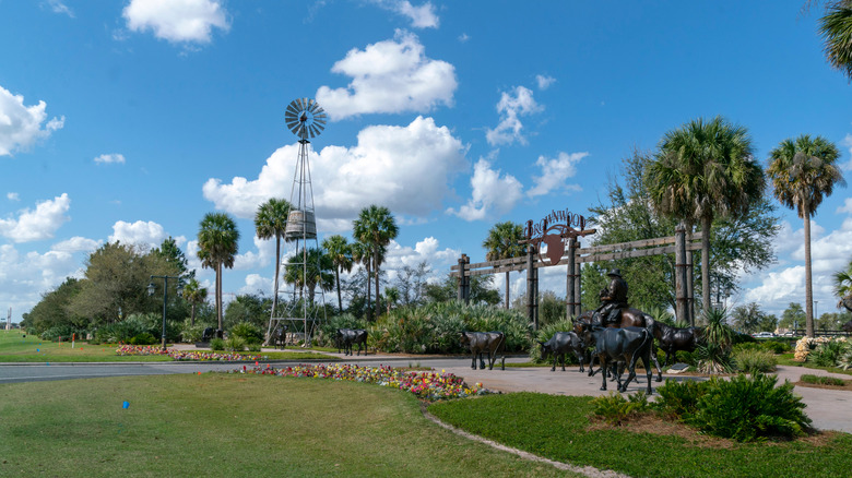 Entrance to Brownwood in the Villages, with a big sign, bronze statues of cowboy and cattle and a windmill