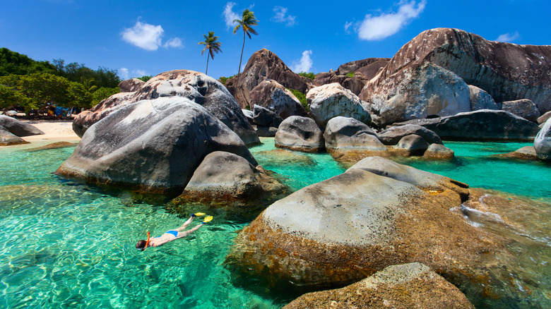 Woman snorkeling near boulders at beach