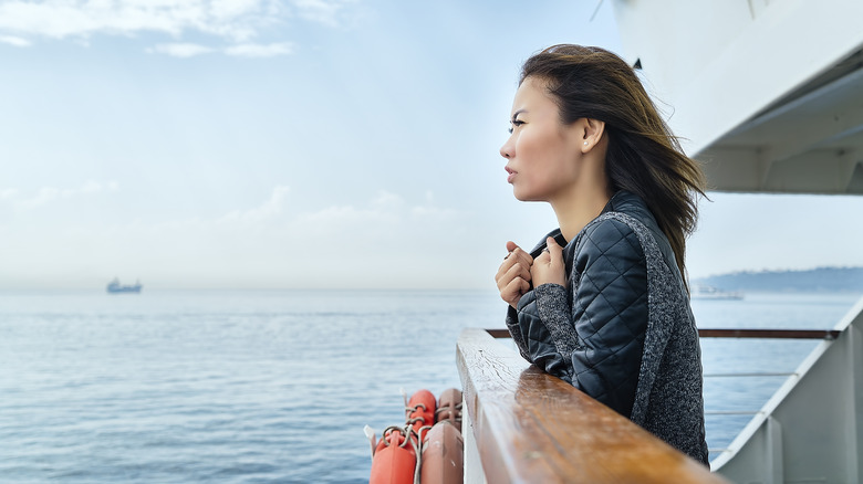 A woman stares wistfully at the sea from the deck of a cruise ship