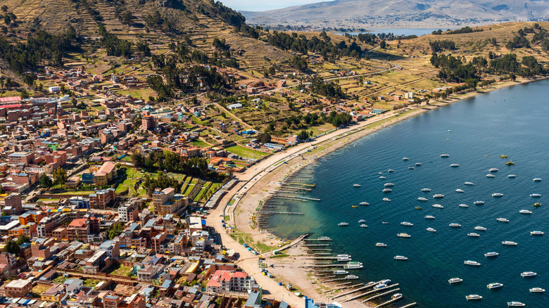 An aerial view of Lake Titicaca with buildings peppered on its shore.