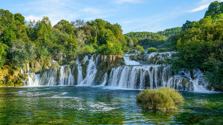 A series of waterfalls amid greenery cascading into a pool below in Krka National Park.